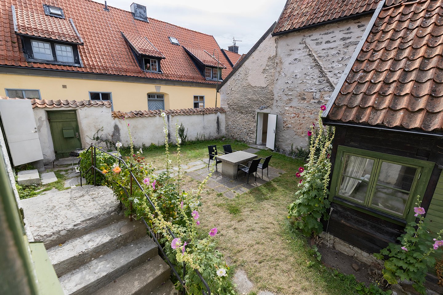 Innergården sett ovanifrån med stentrappa och stockrosor